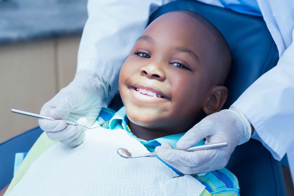 Child sitting a dentist chair getting a check up from a dentist
