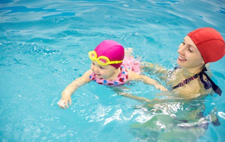 Child swimming with assistance from parent