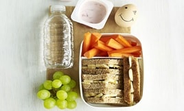 Children's Lunch - A bottle of water, a yogurt, boiled egg, grapes, carrot sticks and a sandwich