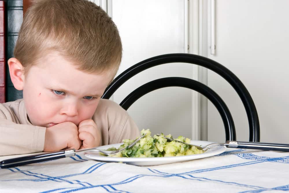 Child looking upset at plate of food
