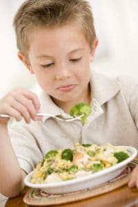 A boy looking apprehensive at some vegetables