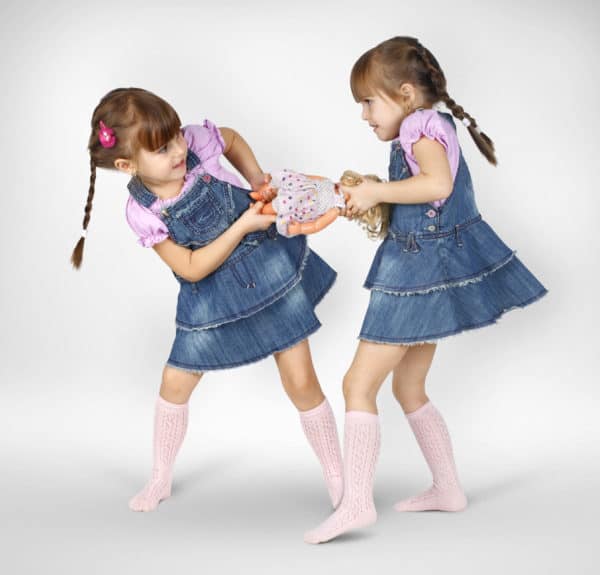 Two children fighting over a toy doll