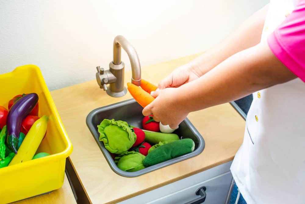 Child playing with toy food in a toy kitchen