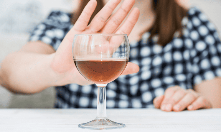 Pregnant woman turning down a glass of wine
