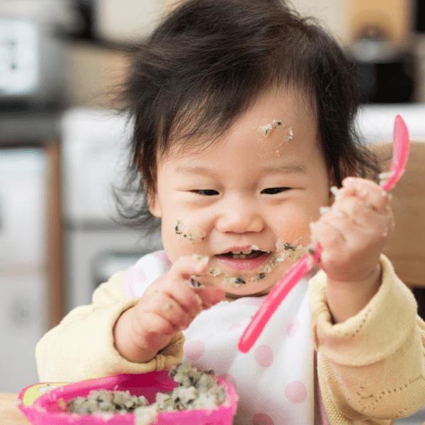 Baby weaning holding a spoon