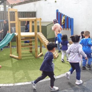 The daily mile in action, children running with nursery practitioners in the garden